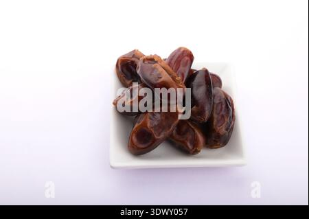 Bowl with dried dates isolated on white background.Fresh dried dates on white background.Plate with dried dates for Ramadan on white background. Stock Photo