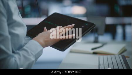 Close Up of Professional Hands Using Tablet to Monitor Stock Market Trends and Green Candlestick Charts. Concept of Mobile Trading, Digital Asset Management, and Real Time Financial Data Tracking. Stock Photo