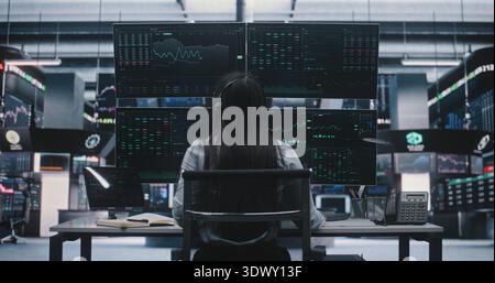 Asian Professional Woman Sits at Desk, Putting on Headset and Preparing to Trade With Coffee. Concept of Independent Wealth Management and Female Leadership in Digital Stock Exchange Industry. Stock Photo