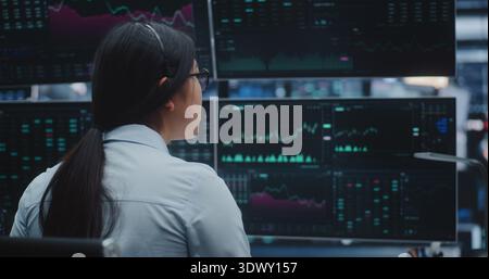 Young Asian Lady Analyzes Complex Financial Graphs in Innovative Digital Office Space. Concept of Big Data Processing, Data Visualization and Advanced Technological Solutions For Global Economy. Stock Photo