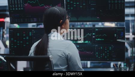 Professional Asian Woman Dressed in Business Attire Works Cutting Edge Station in Massive Exchange Center. Concept of High Productivity Environments and Evolution of Innovative Digital Office. Stock Photo