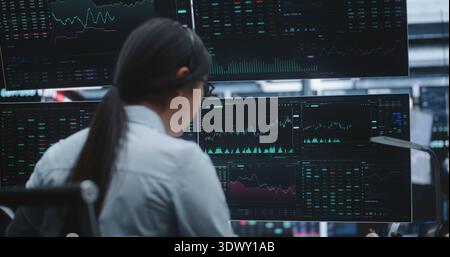 Asian Female Executive Manages Global Portfolios in Huge Digital Stock Exchange. Concept of Market Leadership, Professional Success and Innovative Technology in High Stakes Financial Services. Stock Photo