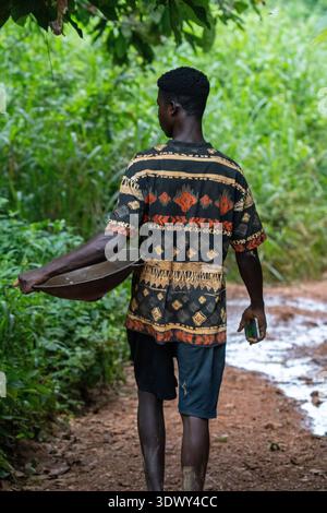 A gold miner walking down a dirt path through the Atewa Forest, Ghana. Stock Photo