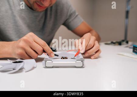 Technician working on computer cooling fan, testing motor with multimeter, checking electronic components during hardware repair and maintenance Stock Photo