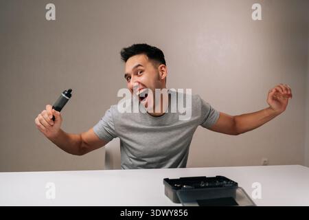 Happy excited man expressing exhilaration and success, holding modern cordless electric screwdriver, having successfully completed home repair project Stock Photo
