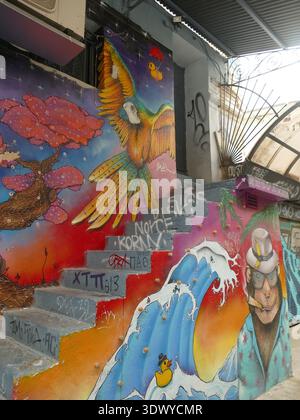 ATHENS, GREECE - MAY 16, 2025 - Vibrant street art featuring colorful parrot soaring above staircase, tropical monkey in hawaiian shirt, sunglasses ne Stock Photo