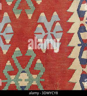 Handwoven kilim rug featuring traditional Anatolian geometric patterns with vibrant red, blue, green, and cream colors, showcasing ethnic textile art Stock Photo