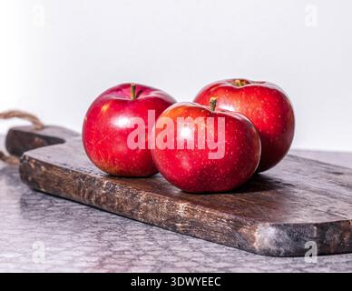 Fresh red apples on rustic wooden cutting board. Stock Photo