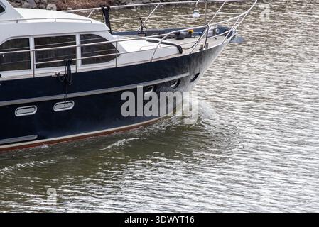 Large Blue Ship Cutting Through Water with Reflected Waves Stock Photo