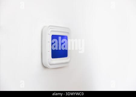 Wall mounted panel of digital thermostat with blue backlit screen Stock Photo