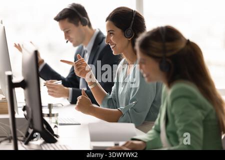 Diverse customer care team in headsets communicating online in office Stock Photo