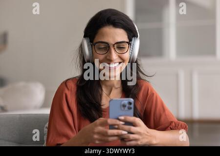 Woman in headphones enjoying music, podcast, or videocalling to family Stock Photo