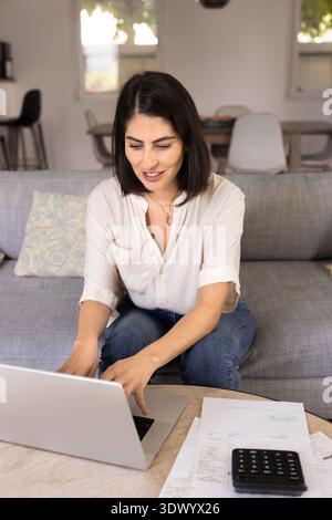 Focused young Latin woman working on personal budget at home Stock Photo
