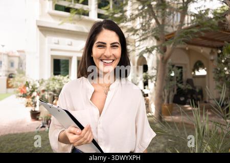 Cheerful young real estate agent woman posing at front door Stock Photo