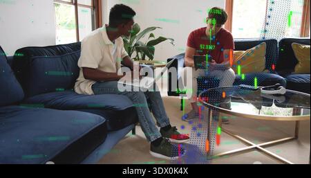 Working two men in white polo, red T-shirt using laptop and tablet in living room, headphones Stock Photo