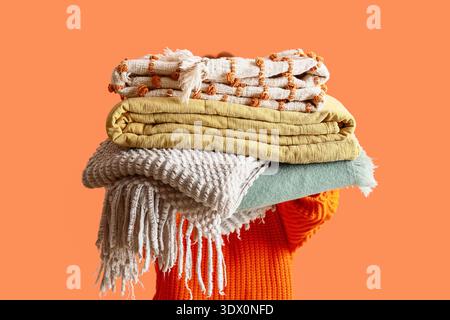 Woman holding warm plaids on orange background Stock Photo