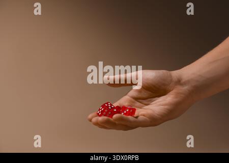 Male hand throwing red game dices on beige background, closeup Stock Photo