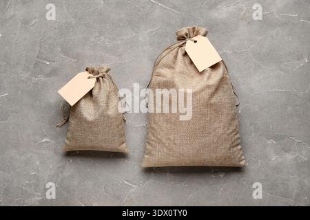 Full sacks with tags on grunge grey background Stock Photo