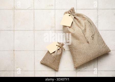 Full sacks with tags on white tile background Stock Photo