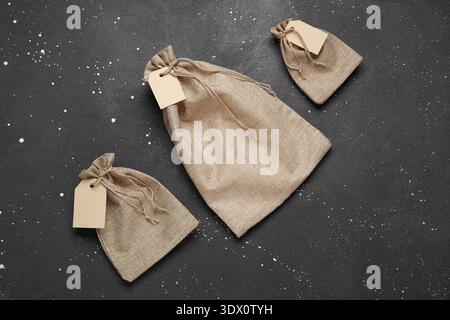 Empty sacks with tags on grunge black background Stock Photo