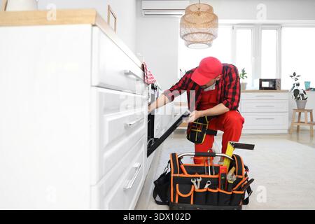 Male technician checking oven in kitchen Stock Photo