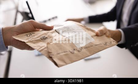 Closeup two businessmen hands giving receiving paper package with label Stock Photo