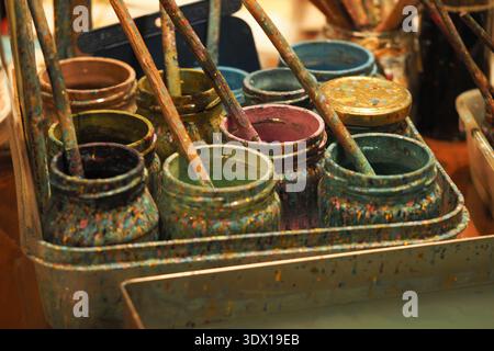 Art supplies in a workshop with jars and brushes on table Stock Photo