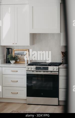 Bright modern kitchen interior featuring white cabinetry, built in oven, marble style backsplash, and clean minimalist design in a contemporary home. Stock Photo