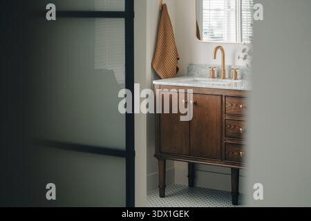Modern bathroom vanity with brass faucet and marble countertop in bright home interior. Stock Photo