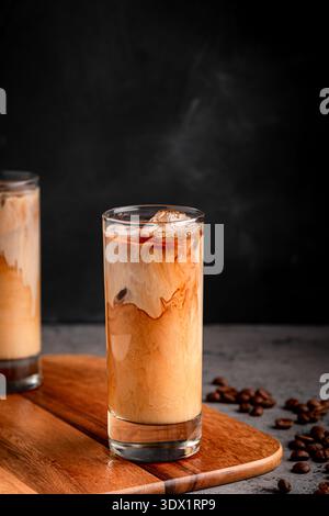 Ice coffee in a glass with cream poured over. Cold summer drink. Stock Photo