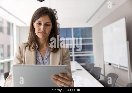 Businesslady standing in conference room with tablet Stock Photo