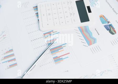 White calculator and pen on colorful business charts and financial report sheets, data analysis for budgeting, accounting, audit, performance metrics Stock Photo