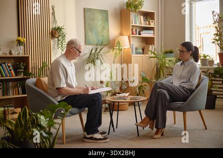 Senior Caucasian Man Discussing Mental Health with Young Adult Woman Therapist Stock Photo