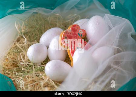 White Easter eggs with decorated bunny cookie in straw nest Stock Photo