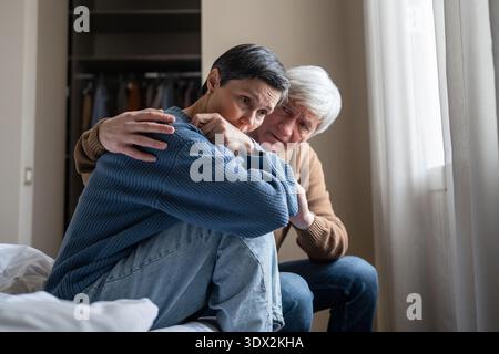 Manipulative abusive husband trying to make peace with depressed apathetic wife after conflict. Stock Photo