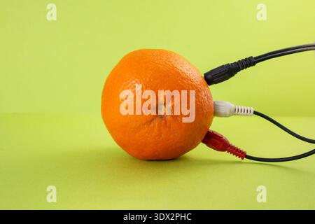 Colorful cables plugged in a orange on bright green background, abstract  energy concept Stock Photo