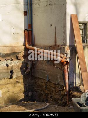 Sewer pipes installed along foundation wall at construction site. Infrastructure repair, plumbing system upgrade and residential renovation concept Stock Photo