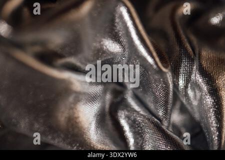 Close-up view of wrinkled black fabric displaying a glossy surface and fine texture, suitable for fashion and textile design projects Stock Photo