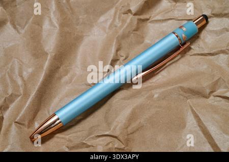 A blue and gold ballpoint pen on crumpled kraft paper Stock Photo