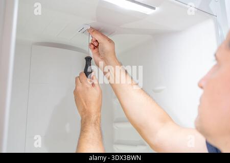 Close-up of male repairman fixing refrigerator with screwdriver at home Stock Photo