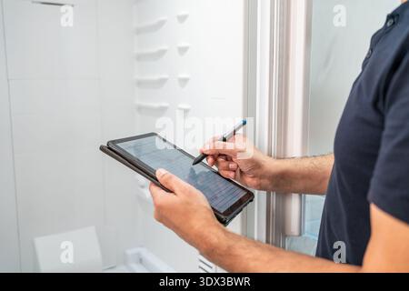 Male technician checking refrigerator and noting the data on the tablet Stock Photo