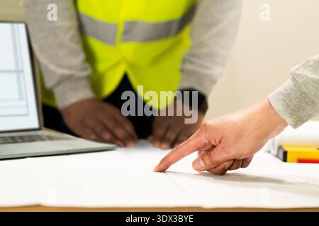 Closeup of team of industrial engineers meeting analyze machinery blueprints consult project on table in manufacturing factory. Working in manufacturi Stock Photo