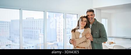 Happy mature couple hugging looking at camera standing in kitchen at home. Stock Photo
