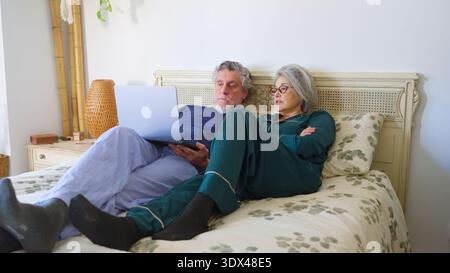Senior couple in bed watching laptop together Stock Photo