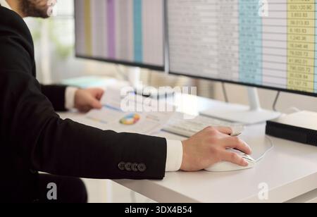 Accountant analyzing invoices on computer with spreadsheets and charts at office Stock Photo