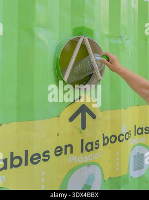 buenos aires, Argentina: 28:02:2026: The hand of a senior citizen throws a plastic bottle into a recycling bin in a square. Stock Photo