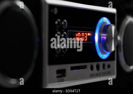 A modern FM stereo radio with a digital display and bright backlight. Side view in dark tones. Stock Photo