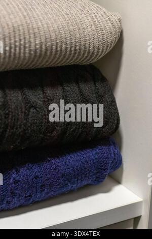 A stack of folded cable-knit sweaters, which are classic winter apparel items often crafted from wool or cashmere for warmth Stock Photo