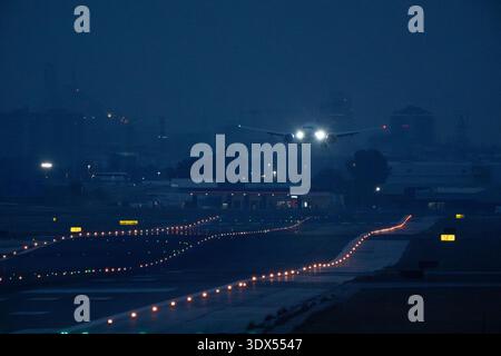 Large airplane taxiing on illuminated runway Stock Photo
