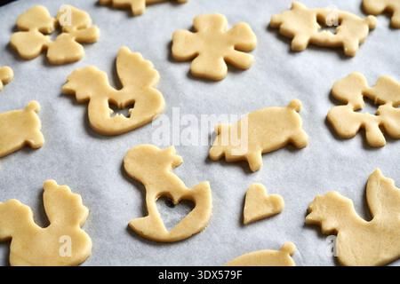 Linzer cookies with Easter motives cut out from raw pastry dough on baking paper Stock Photo